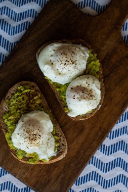 Haşlanmış yumurta ile avokado tost. Koyu ahşap yüzeyde hizmet