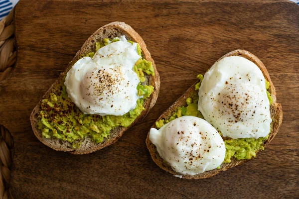 Haşlanmış yumurta ile avokado tost. Koyu ahşap yüzeyde hizmet