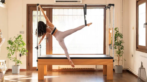 Pilates yapan kadın, pilates yapan Cadillac 'ın üzerinde geriniyor.