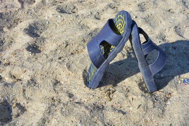 Öğleden sonra Karadeniz'in sığ deniz kabuğu plajı ile sarı kum üzerinde sarı çizgili mavi kadın terlik