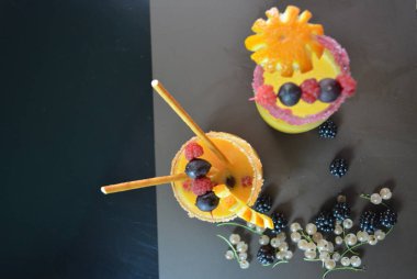 İki bardak portakal suyu dekore kuş üzümü, böğürtlen, portakal, Bektaşi, ahududu, payet, sahur kahverengi mat arka plan üzerinde