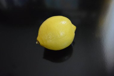 Taze meyve, parlak siyah arka planda sarı bir limon..