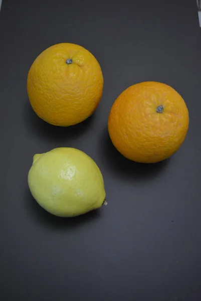Świeże Owoce Dwa Pomarańcze Jedną Żółtą Cytryną Ciekawym Matowym Tle — Zdjęcie stockowe