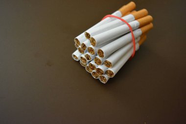 Paketteki sigaralar kahverengi bir arka planda kırmızı lastik bantla sabitlenir..