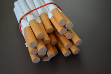 Paketteki sigaralar kahverengi bir arka planda kırmızı lastik bantla sabitlenir..