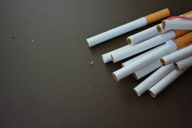 Paketteki sigaralar kahverengi bir arka planda kırmızı lastik bantla sabitlenir..