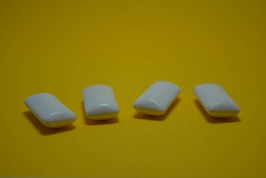 Parlak sarı kağıdın üzerinde sakızdan çıkan beyaz yastıklar var..