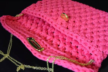 Bir siyah parlak arka plan üzerinde pembe Bayan dokuma altın yatağı ve bir konserve açacağı ve bir yansıma ile omzuna çantam