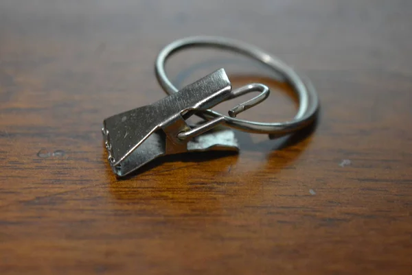 Metal clip of a crocodile with a ring on a brown lacquered wooden background