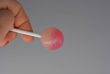 Kadın elinde tatlı çilek şeker, beyaz ve pembe renk beyaz arka plan, chupik, chupa chups beyaz plastik çubuk üzerinde yuvarlak emme şeker