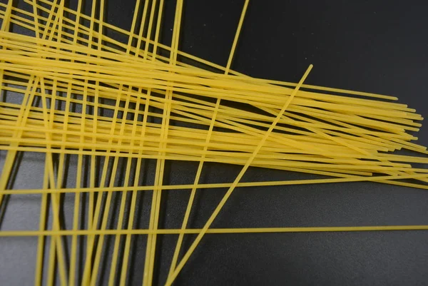 Long dry vermicelli, Italian pasta spaghetti from hard wheat varieties in packs on an interesting black background