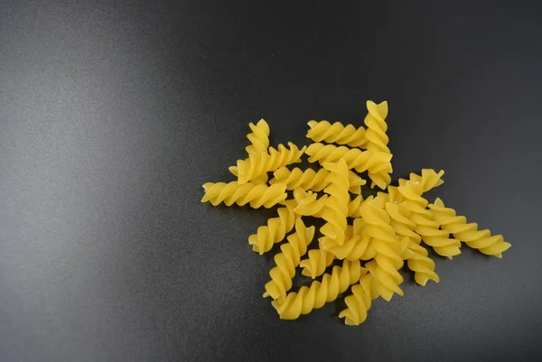 意大利黄色和干燥的粉丝螺旋 意大利面食与硬质合金小麦和块在一个非常美丽的黑色背景 — 图库照片