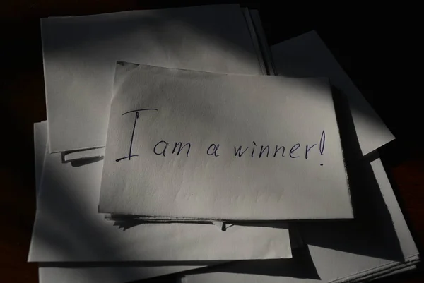 The inscription on paper is i am a winner and a lot of papers on business wooden lacquered table