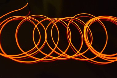 Parlayan kırmızı malzeme, ince parlak iplikler. Yanan tel, güzel dokusal ışık çizimi. Sanat soyutlama ışık lif, düğüm çizgileri ve soyutlama.