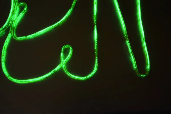 Lime green lighting with a specific pattern. Woven filaments, cable, wires with outgoing light. Neon electroluminescent wire with an inscription and letters open.