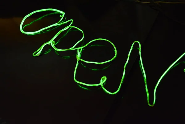 Lime green lighting with a specific pattern. Woven filaments, cable, wires with outgoing light. Neon electroluminescent wire with an inscription and letters open.