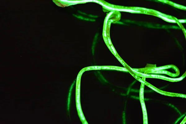 Toxic green lime lighting with a specific pattern. Woven filaments, cable, wires with outgoing light. Neon electroluminescent wire in the form of night lighting.