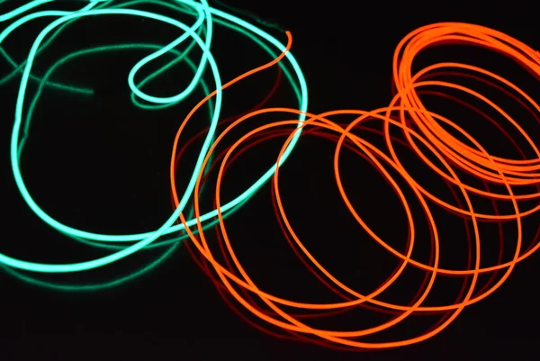 Neon green and red thin wire. Luminous wires, decoration and illumination of the surface. Electroluminescent wire, lighting objects and light base.