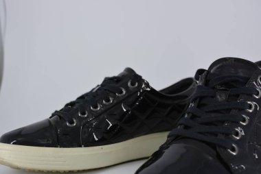 Gençlik siyah patent deri ayakkabı, kalın beyaz taban ve siyah bağcıklı spor ayakkabıları. Beyaz arka planda bulunan ilginç bir stil ve malzeme ile şık ve zarif ayakkabılar.