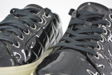 Gençlik siyah patent deri ayakkabı, kalın beyaz taban ve siyah bağcıklı spor ayakkabıları. Beyaz arka planda bulunan ilginç bir stil ve malzeme ile şık ve zarif ayakkabılar.