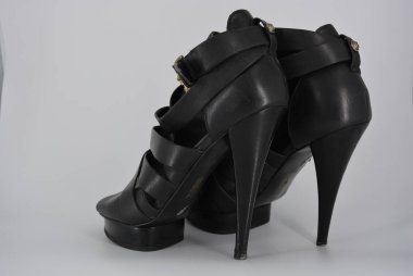 Yüksek topuklu gerçek cowhide mat deri seksi çekici siyah kadın sandalet. Deri bantlardan yapılmış moda kadın ayakkabıları, üzerlerinde altın tokalı kurdeleler.