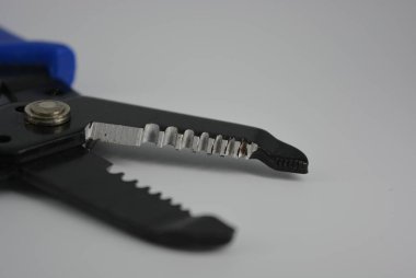 Çelik tellerden yalıtım ıstırmak için çok fonksiyonlu cihaz. Kabloları ve telleri sıyırmak için el aletleri, beyaz arka plan üzerinde mavi kolları ile yonga ları.