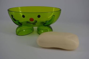 Kozmetik sabun ile parlak yeşil şeffaf sabun çanak beyaz bir arka plan üzerinde yer almaktadır. Bir gülümseme, neşeli ve iyi bir ruh hali ile Pozitif sabun çanak.