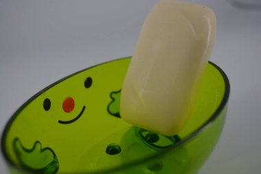 Kozmetik sabun ile parlak yeşil şeffaf sabun çanak beyaz bir arka plan üzerinde yer almaktadır. Bir gülümseme, neşeli ve iyi bir ruh hali ile Pozitif sabun çanak.