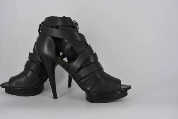 Sexy glamorous black women's sandals from genuine cowhide matte leather on high heels. Fashion women's shoes made of leather bands, ribbons with gold clasp on them.