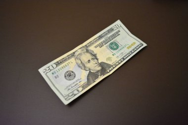 Kağıt notta yirmi Amerikan doları tutarında, 20 $ mat kahverengi bir arka plan üzerinde yatıyor. Amerika Birleşik Devletleri Para Birimi, nakit ve finansal akışlar, para kazanma, bankacılık işlemleri ve para transferi, maaş.