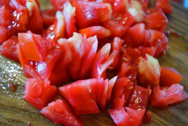 Taze kırmızı domates ahşap kahverengi bir tahta üzerinde küçük parçalar halinde doğranmış.