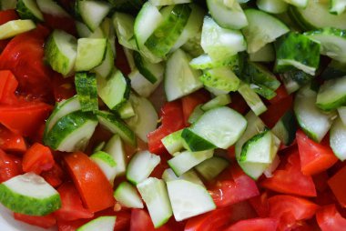 Taze sağlıklı sebzeler, yaz salatası için yeşil salatalık ve kırmızı domates küçük dilimler, salata için malzemeler.