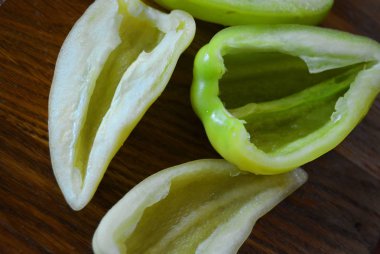 Yeşil tatlı biber dilimleri kahverengi ahşap mutfak tahtası üzerinde yalan.