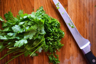 Salata için yeşil yıkanmış taze maydanoz ve doğranmış maydanoz bir demet ahşap bir mutfak tahtası üzerine serilir.