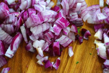 Kırmızı ince doğranmış sulu soğan lezhin kahverengi ahşap mutfak tahtası üzerinde.