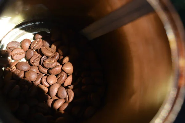 In a metal coffee can, a handful of coffee beans illuminated by sunligh