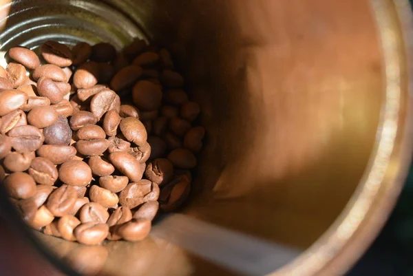 In a metal coffee can, a handful of coffee beans illuminated by sunligh