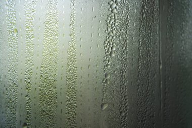 Buharla buğulanmış şeffaf cam, ilginç ışık aydınlatması ve cilası ile tüm yüzeyde su yoğuşması ve küçük damlalar.
