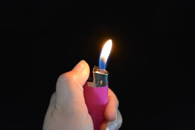 Yangın ve dahil pembe plastik çakmak siyah parlak bir yüzey üzerinde bir kadın elinde yalan.