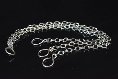 İlginç bir renk ile bir aksesuar olarak şık metal zincirleri parlak siyah bir yüzey üzerinde yer almaktadır.