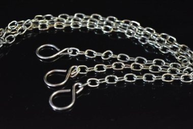 İlginç bir renk ile bir aksesuar olarak şık metal zincirleri parlak siyah bir yüzey üzerinde yer almaktadır.