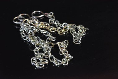 İlginç bir renk ile bir aksesuar olarak şık metal zincirleri parlak siyah bir yüzey üzerinde yer almaktadır.