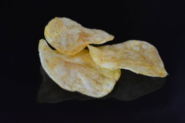 Ambalajından lezzetli, gevrek patates cipsi yansımaile siyah parlak bir yüzey üzerinde yalan.