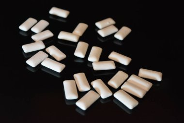 Beyaz lezzetli yastıklar, siyah parlak bir yüzey üzerinde bulunan sakız yastıklar.