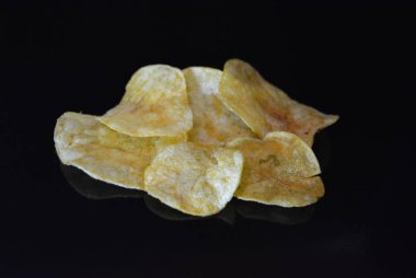 Ambalajından lezzetli, gevrek patates cipsi yansımaile siyah parlak bir yüzey üzerinde yalan.