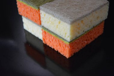 Sıradan yemekler, temizlik ve yıkama plakaları ve çatallar için sünger siyah parlak bir yüzey üzerinde yer almaktadır.