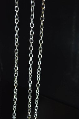 İlginç bir renk ile bir aksesuar olarak şık metal zincirleri parlak siyah bir yüzey üzerinde yer almaktadır.