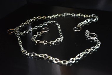 İlginç bir renk ile bir aksesuar olarak şık metal zincirleri parlak siyah bir yüzey üzerinde yer almaktadır.