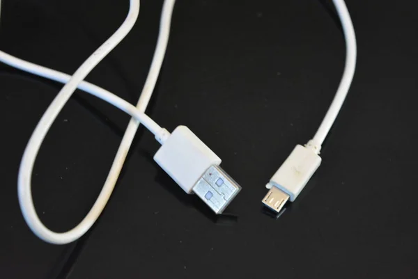White long wire for computer and office equipment, Usb cable microusb connector on a black glossy surface.