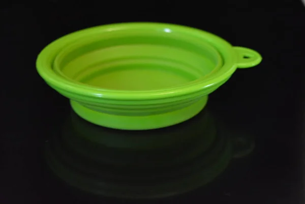 绿色折叠和多功能橡胶板 黑色光泽表面上带有塑料边缘的碗 — 图库照片